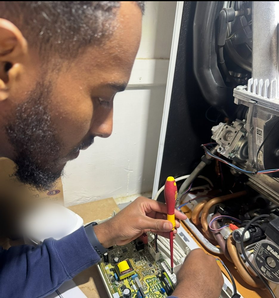 Gas engineer working on a boiler circuit board with an insulated screwdriver